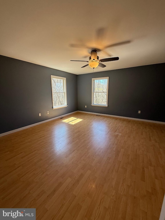 empty room featuring baseboards, a ceiling fan, and wood finished floors