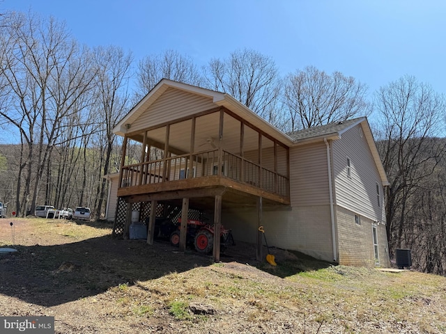 back of property featuring a wooden deck, a shingled roof, brick siding, and central AC unit