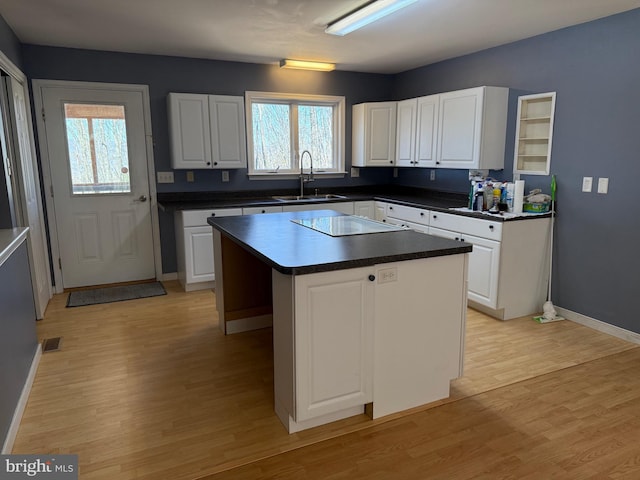 kitchen featuring light wood-type flooring, black electric cooktop, white cabinets, and a sink