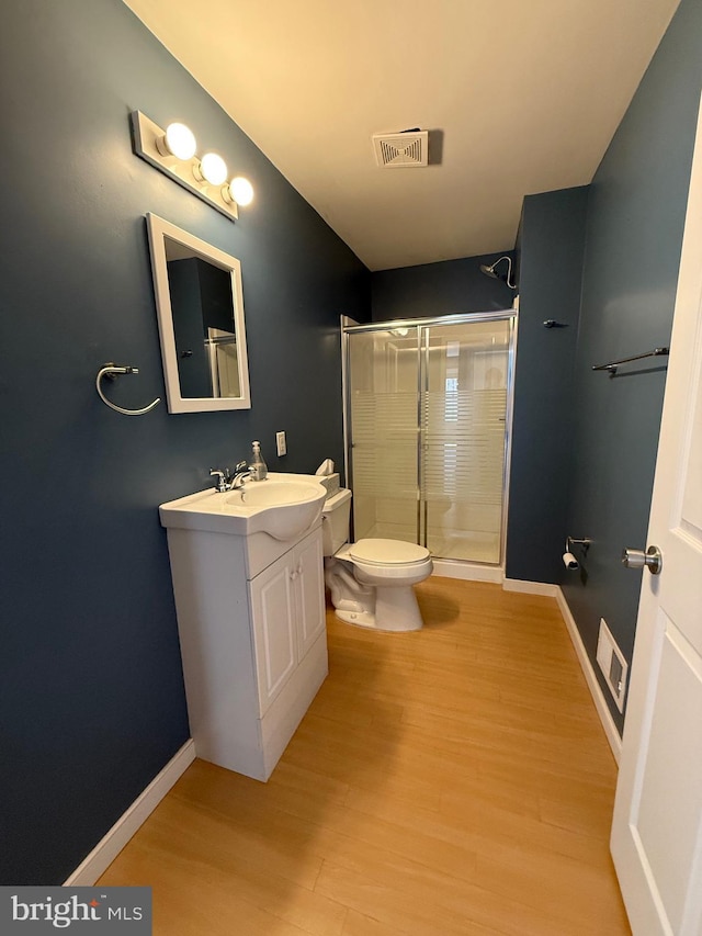 bathroom featuring toilet, baseboards, wood finished floors, a shower stall, and vanity