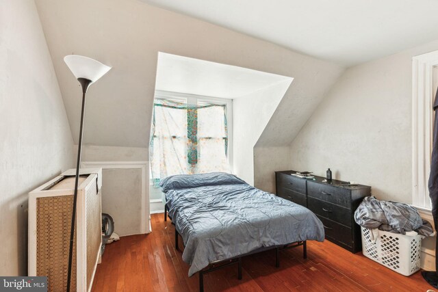 bedroom featuring hardwood / wood-style flooring, vaulted ceiling, and radiator