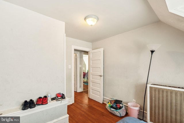 bedroom with heating unit, wood finished floors, and radiator