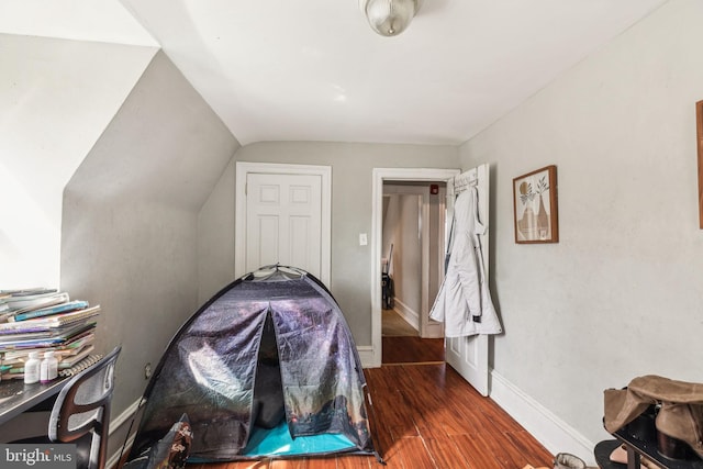 bedroom with baseboards, vaulted ceiling, and wood finished floors