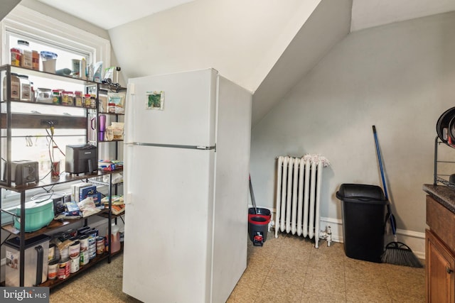 interior space featuring radiator heating unit, tile patterned floors, vaulted ceiling, and freestanding refrigerator