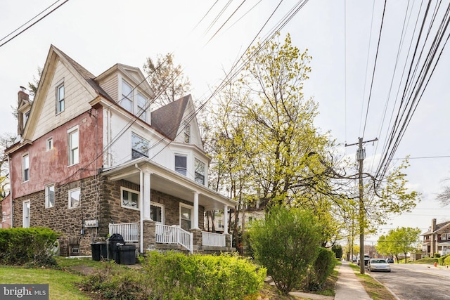victorian home featuring a porch and stone siding