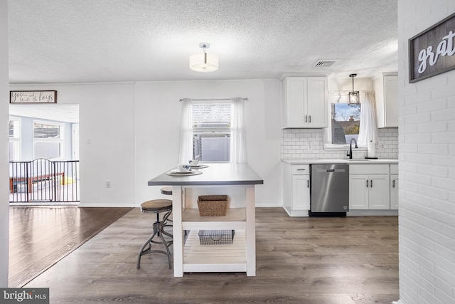 kitchen featuring backsplash, stainless steel dishwasher, white cabinetry, and dark wood-type flooring