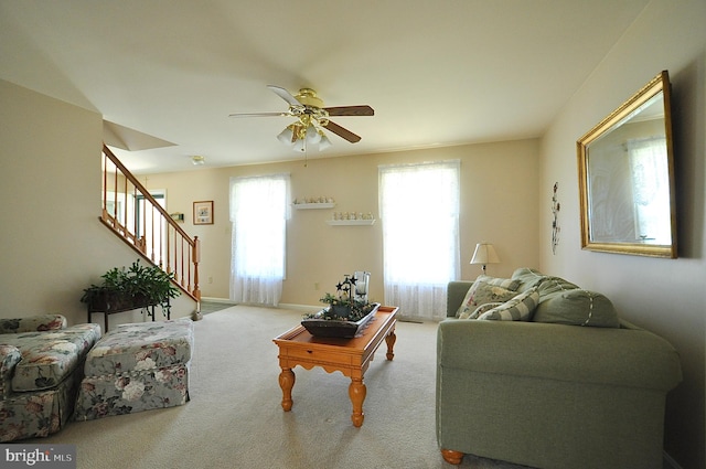 living room featuring stairway, carpet floors, baseboards, and ceiling fan