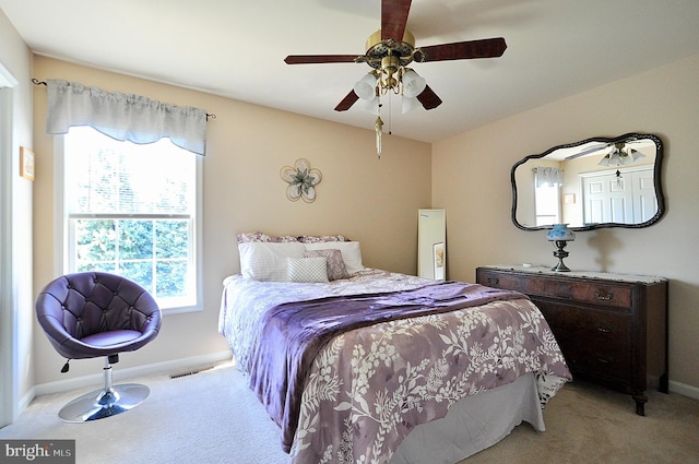 bedroom featuring baseboards, visible vents, light colored carpet, and multiple windows