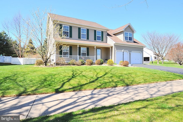 view of front of home with driveway, fence, a front yard, and covered porch