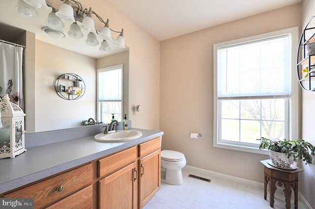 full bathroom featuring toilet, vanity, visible vents, and baseboards