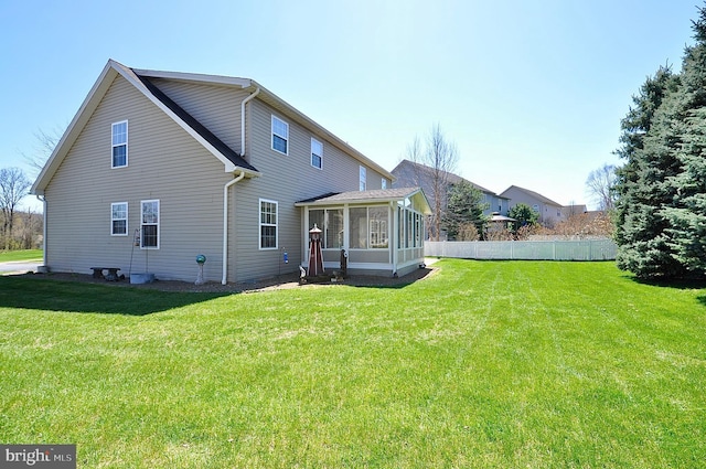 rear view of property featuring a sunroom, fence, and a yard