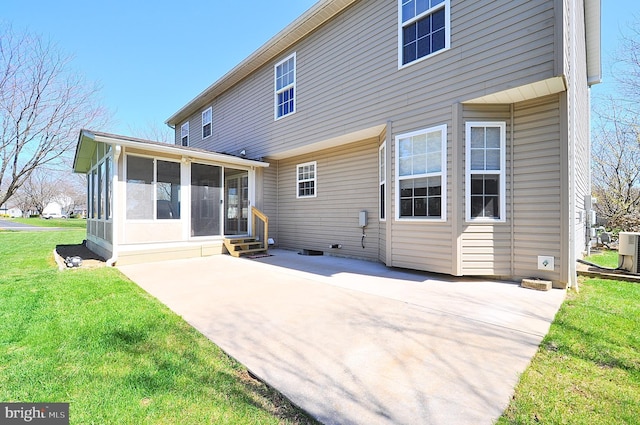 rear view of house featuring entry steps, a lawn, a sunroom, and a patio