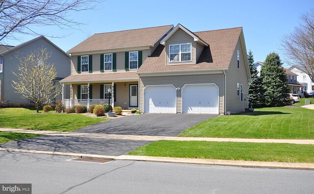 traditional home featuring a garage, a porch, a front lawn, and aphalt driveway