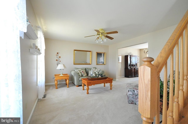 carpeted living area featuring stairway, a ceiling fan, and baseboards