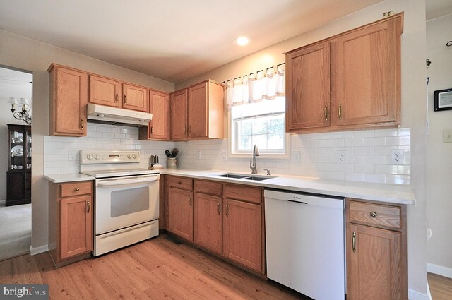 kitchen with light wood-style flooring, a sink, white appliances, light countertops, and under cabinet range hood