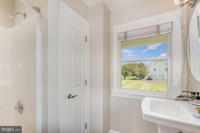 full bath with baseboards, a sink, and walk in shower