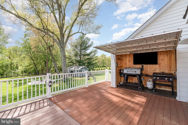 deck featuring grilling area, a shed, a fenced backyard, an outbuilding, and a lawn