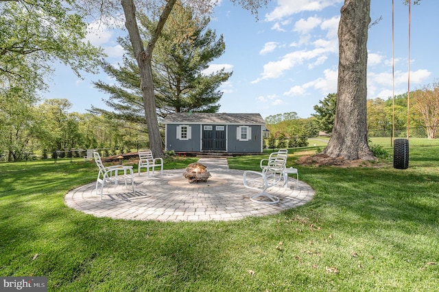 view of yard with an outdoor structure, an outdoor fire pit, and a patio area