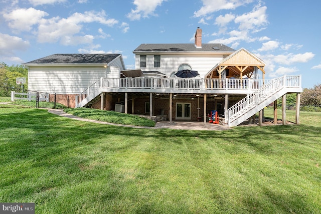 back of property featuring a lawn, a deck, and stairway