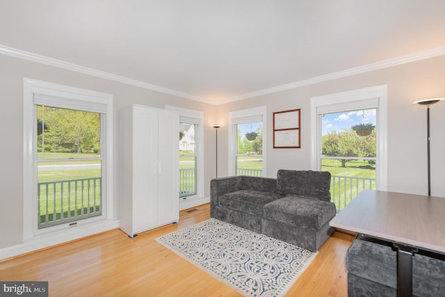 living area with crown molding, light wood-style flooring, and a wealth of natural light