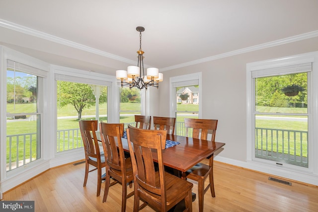 dining space featuring crown molding, a chandelier, visible vents, and light wood-style floors