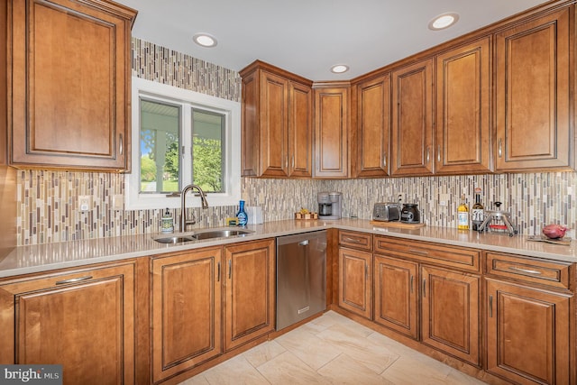 kitchen featuring a sink, light countertops, stainless steel dishwasher, and brown cabinetry