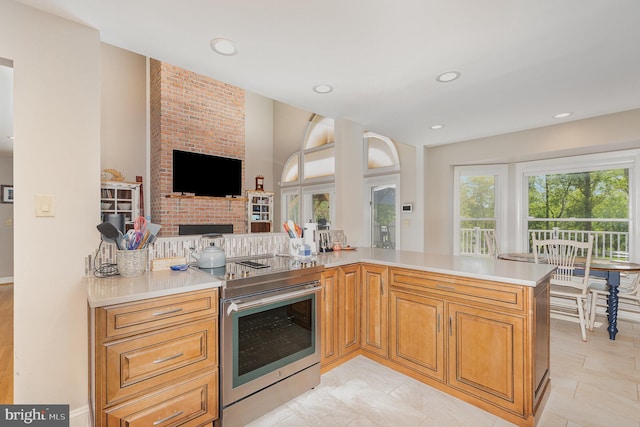 kitchen featuring stainless steel range with electric stovetop, light countertops, a brick fireplace, recessed lighting, and open floor plan