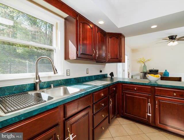 kitchen with a sink, reddish brown cabinets, light tile patterned floors, healthy amount of natural light, and recessed lighting