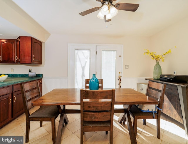 dining space featuring a wainscoted wall, light tile patterned floors, and ceiling fan