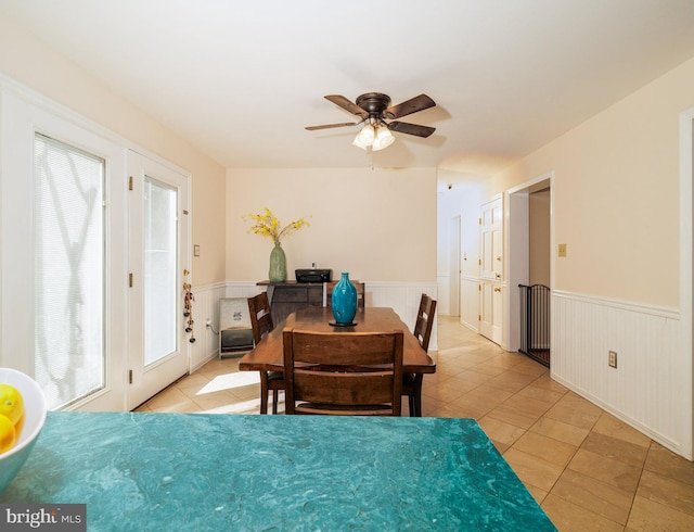dining room featuring light tile patterned floors, wainscoting, and a ceiling fan