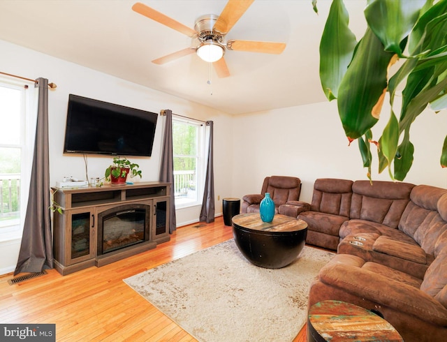 living room with wood finished floors, ceiling fan, and a glass covered fireplace