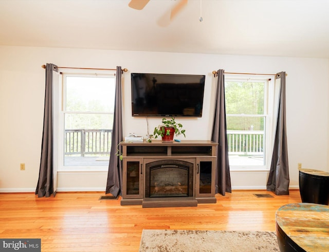 living area featuring wood finished floors, baseboards, and ceiling fan
