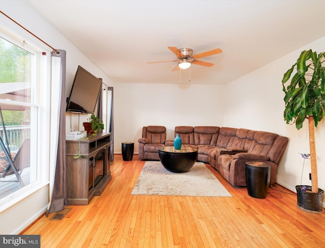 living area featuring light wood-style floors, healthy amount of natural light, ceiling fan, and baseboards
