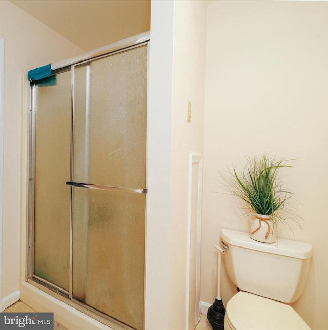 bathroom with an enclosed shower, toilet, and baseboards
