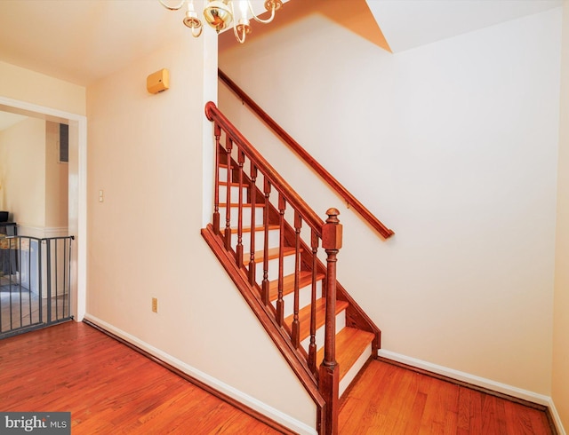 stairway featuring a chandelier, wood finished floors, and baseboards