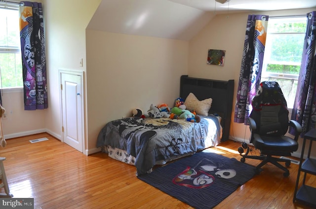 bedroom featuring hardwood / wood-style flooring, vaulted ceiling, and baseboards