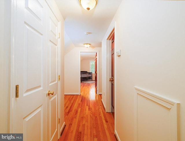 hallway with light wood-type flooring and lofted ceiling