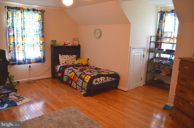 bedroom with hardwood / wood-style floors, vaulted ceiling, and baseboards