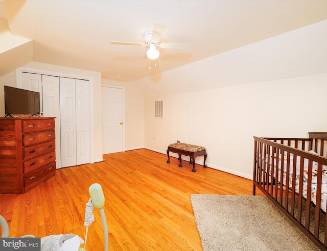 bedroom with wood finished floors, lofted ceiling, baseboards, ceiling fan, and a closet