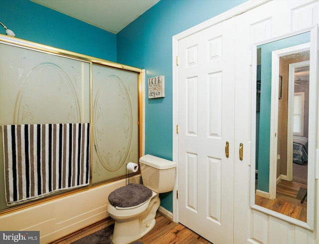 full bath featuring wood finished floors, toilet, enclosed tub / shower combo, and baseboards