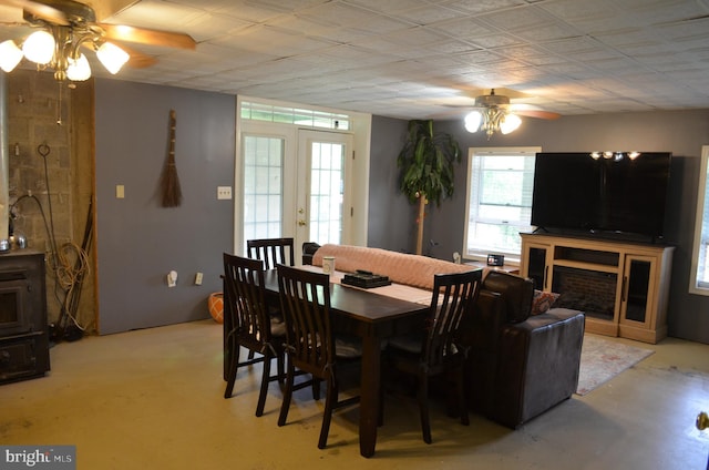dining space with a ceiling fan, a fireplace, and concrete floors