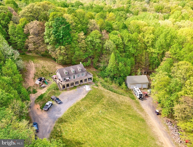 aerial view of property and surrounding area featuring a heavily wooded area