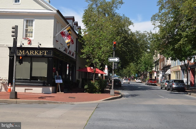 view of asphalt road with curbs, sidewalks, and street lights