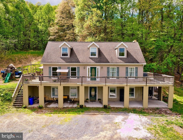 view of front of home with a wooden deck, a patio, a view of trees, and stairway