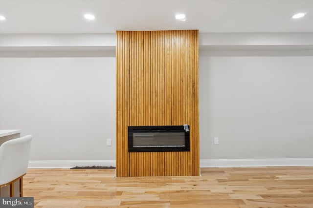 details featuring baseboards, a large fireplace, wood finished floors, and recessed lighting