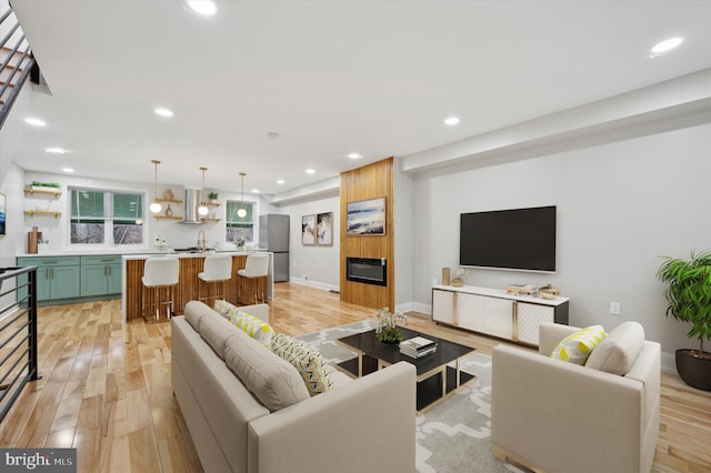living area featuring light wood-type flooring, a fireplace, baseboards, and recessed lighting