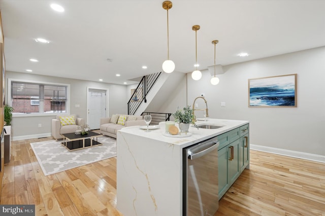 kitchen featuring light wood-style flooring, a sink, green cabinetry, baseboards, and dishwasher