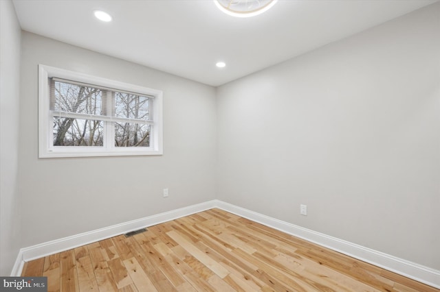 empty room with visible vents, wood finished floors, baseboards, and recessed lighting