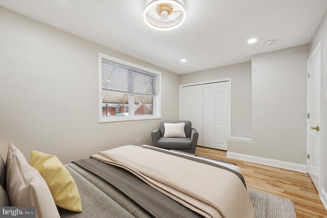 bedroom with light wood-style flooring, baseboards, recessed lighting, and a closet