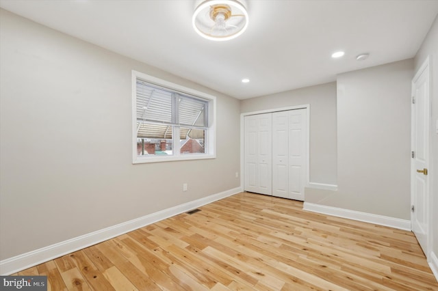 unfurnished bedroom featuring a closet, light wood-style floors, visible vents, and baseboards